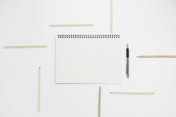 Notebook with pen and pencil on white paper background, for graphic designers presentations and portfolios concept.