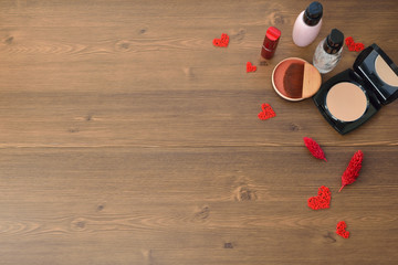 cosmetics on wooden table: powder, lipstick, eye shadow and perfume