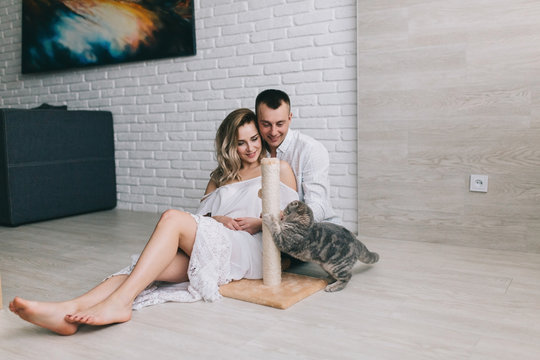Young couple with scottish fold cat flirting in home.