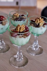 Individual portions of yoghurt with crunch, grapes, coconut flakes and walnut