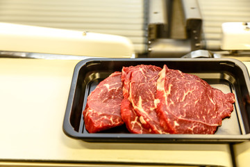 The meat processing plant. The beef is cut into steaks lies in a plastic container.
