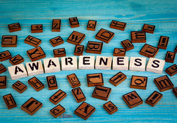 awareness word written on wood block. Wooden alphabet on a blue background.