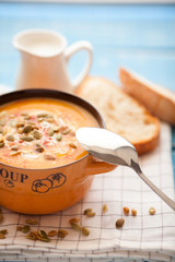 Homemade pumpkin soup with cream, bread, greens and pumpkin seeds on a wooden background. Top viev