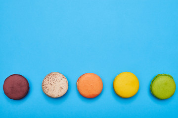 Top view of five colorful macaroons isolated over blue flatlay