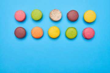Fototapeta na wymiar Some macaroons arranged in two lines isolated over blue flatlay