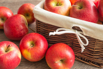 Juicy apples in the basket and scattered on the table.