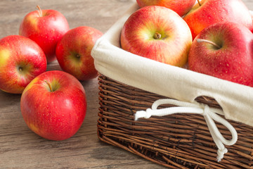 Juicy apples in the basket and scattered on the table.