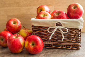 Juicy apples in the basket and scattered on the table.