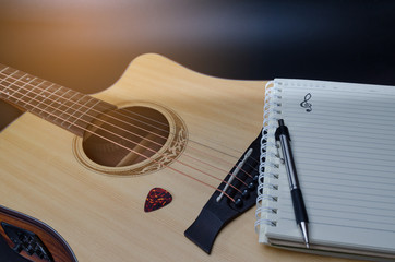 Notebook and pencil on guitar for writing music , Concept of music