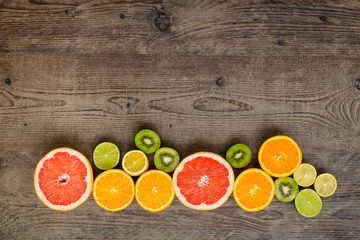 Slices fresh fruits on a brown board with place for a text.