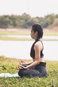 Young asian woman in sportswear meditating on yoga mat, vintage tone
