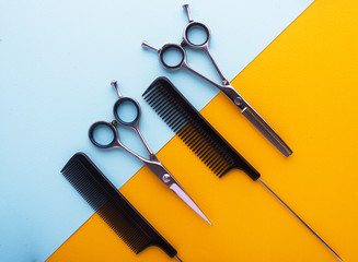 combs and hairdresser tools on color cardboard background top view