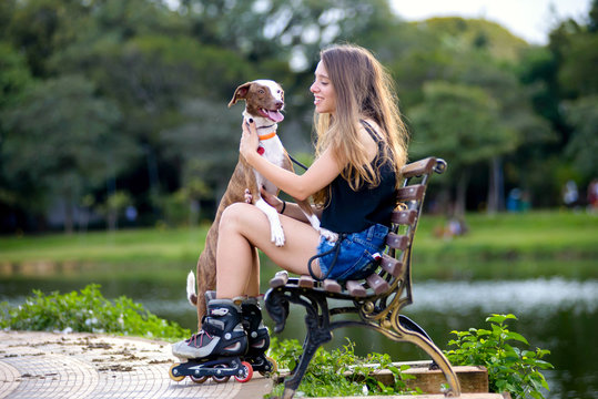 girl and dog smiling sitting down on a bench at a park on a summer day