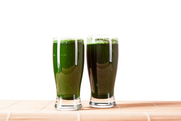 Green pills, green powder, green drink and wheat grass blades isolated on white background. Chlorella, spirulina, wheat grass and barley grass. Healthy natural herbal medicine, healthy lifestyle.