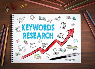 Keywords Research Business Concept. Notebooks, pen and colored pencils on a wooden table.
