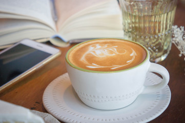 Top view of coffee cup and green tea cake , smart phone , book , on table in coffee shop relax time