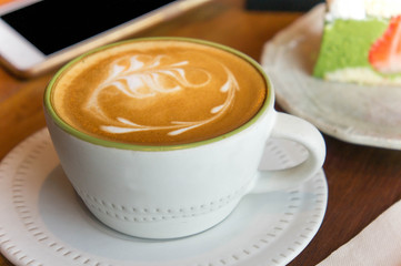 Top view of coffee cup and green tea cake , smart phone , book , on table in coffee shop relax time