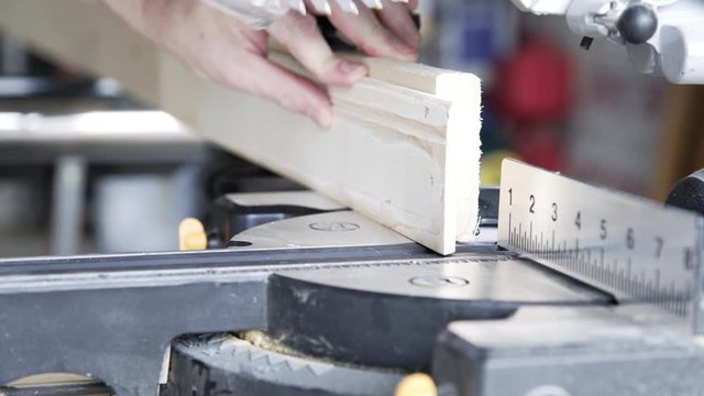 A homeowner handyman type using a power miter saw to cut baseboard for a home improvement project.