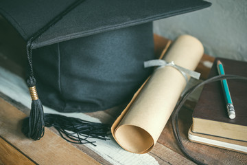 graduation cap, hat with degree paper on wood table graduation concept.