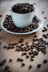 coffee cup filled by coffee beans on wooden background