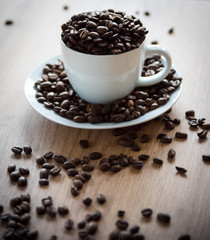 coffee cup filled by coffee beans on wooden background