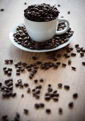 coffee cup filled by coffee beans on wooden background