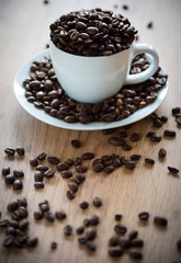 coffee cup filled by coffee beans on wooden background