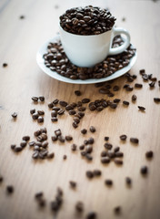 coffee cup filled by coffee beans on wooden background