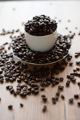 coffee cup filled by coffee beans on wooden background