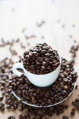 coffee cup filled by coffee beans on wooden background