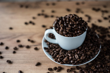coffee cup filled by coffee beans on wooden background