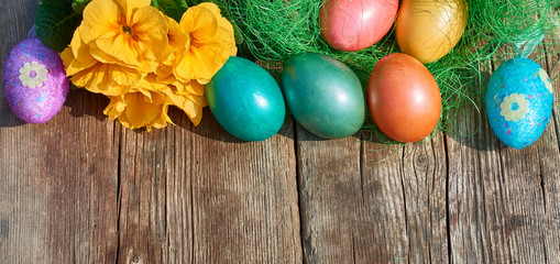 Obraz na płótnie Canvas Easter eggs in nest on old wooden background with yellow flower