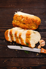 Baguette with garlic, dill and cheese sliced on a wooden table