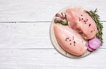 Raw chicken breast fillets on wooden cutting board