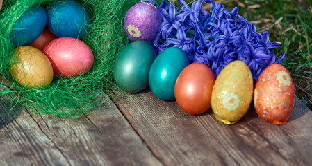 Easter eggs in nest on old wooden background with blue hyacinths flower