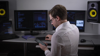 Fototapeta na wymiar Underground organization. On a table computers. The person in a light shirt and points looks at article in the smartphone, tries to understand information