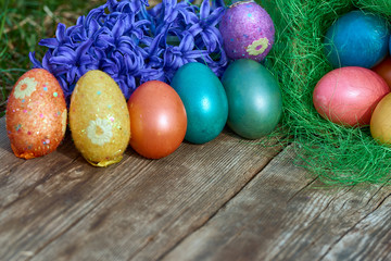 Easter eggs in nest on old wooden background with blue hyacinths flower