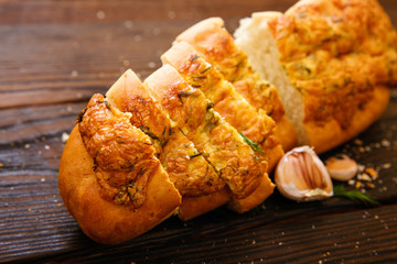 Baguette with garlic, dill and cheese sliced on a wooden table