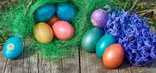 Fototapeta na wymiar Easter eggs in nest on old wooden background with blue hyacinths flower