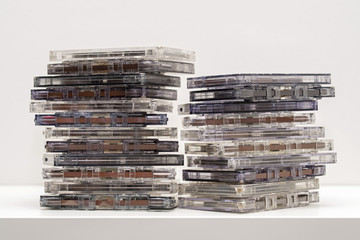 Stack of old dirty audio cassettes on the white shelf