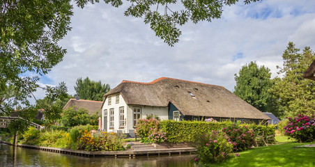 Fototapeta na wymiar Panorama of a white farm house with thatched roof in Giethoorn