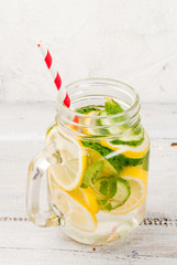Infused detox diet refreshing water with cucumber and lemon. On white wooden table, in Mason Jar copy space vertical