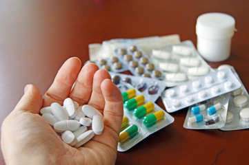 Packaging medical pills on a wooden table and in the hands of a woman