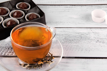 Cup of hot tea with dark chocolate on old wooden table