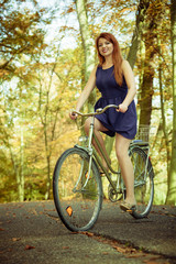 Fototapeta na wymiar Redhead lady cycling in park.