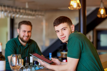 Waiters, bartenders barista rest with the tablet in a break cafe bar restaurant.