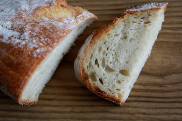 Brotscheibe mit Brotlaib auf Holztisch