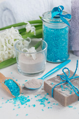 Cosmetic clay powder, homemade clay soap and blue sea salt on white background.