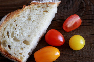 Brotscheibe mit farbigen Tomaten auf Holztisch