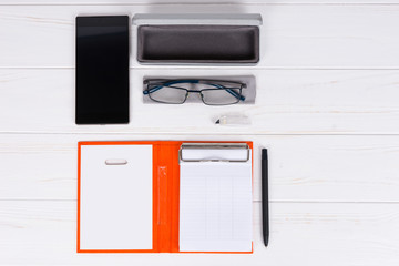 Open diary with a pen, glasses and open case for glasses near mobile phone